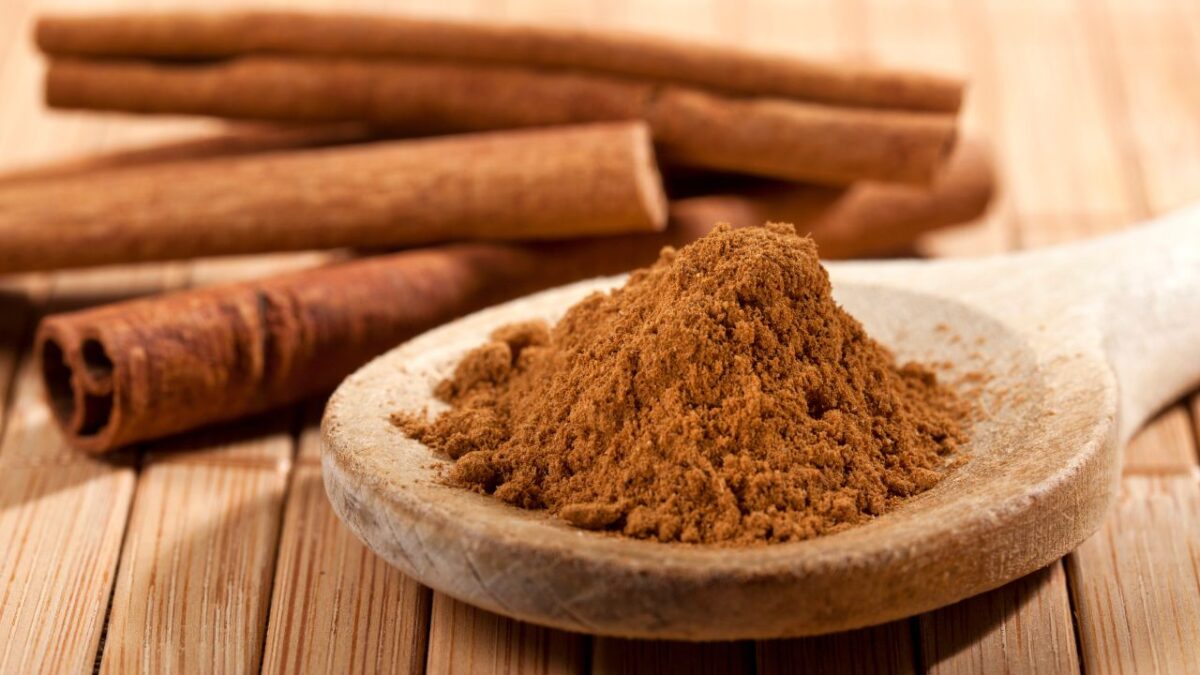 Cinnamon Powder on spoons with Cinnamon sticks on the side